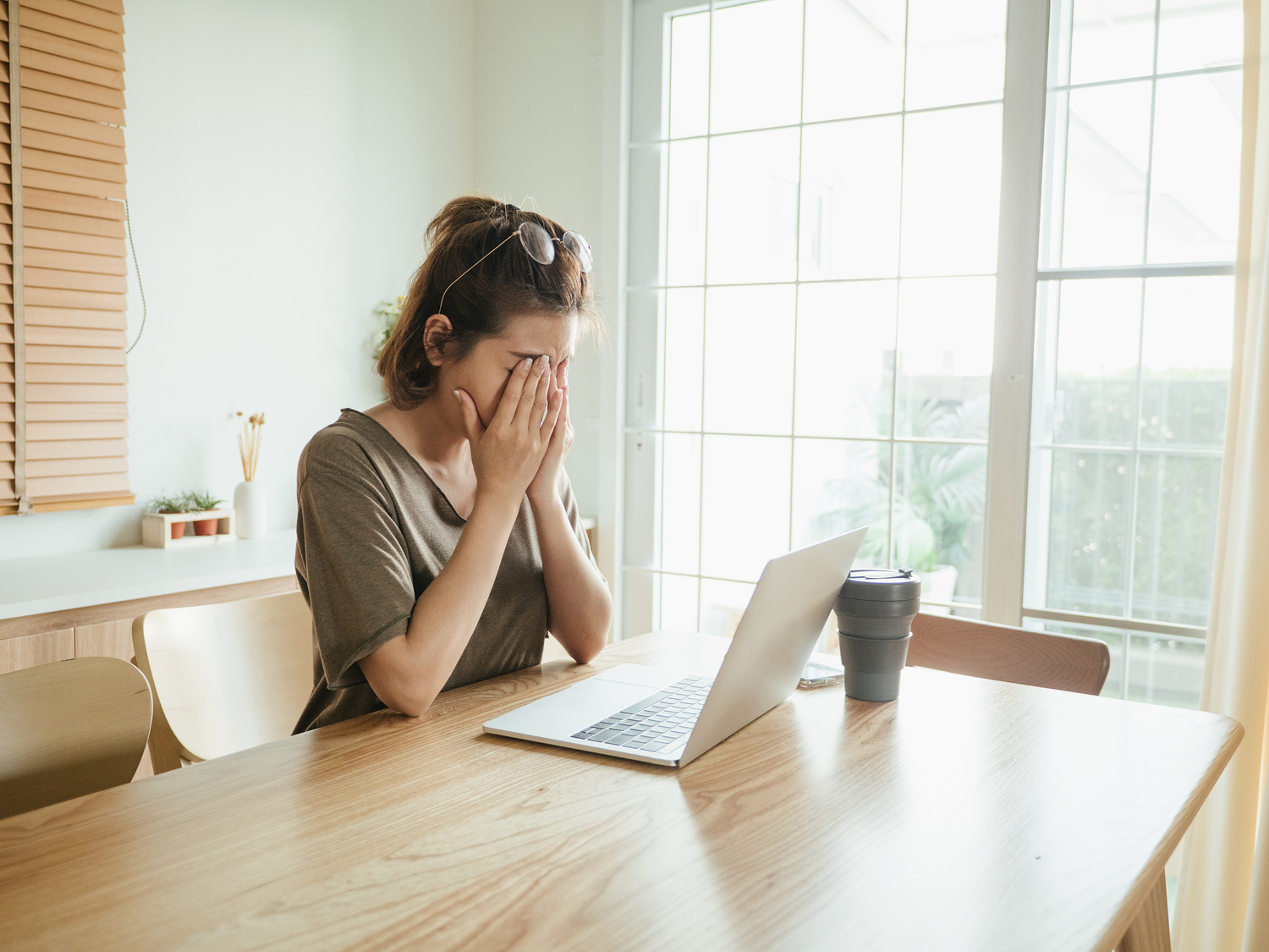 Asian woman struggling with using laptop at home.